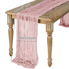 A pink semi-sheer gauze table runner draped over a wooden table.