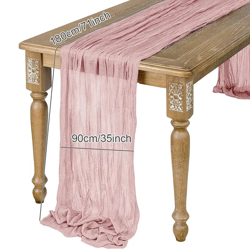 A pink semi-sheer gauze table runner draped over a wooden table.