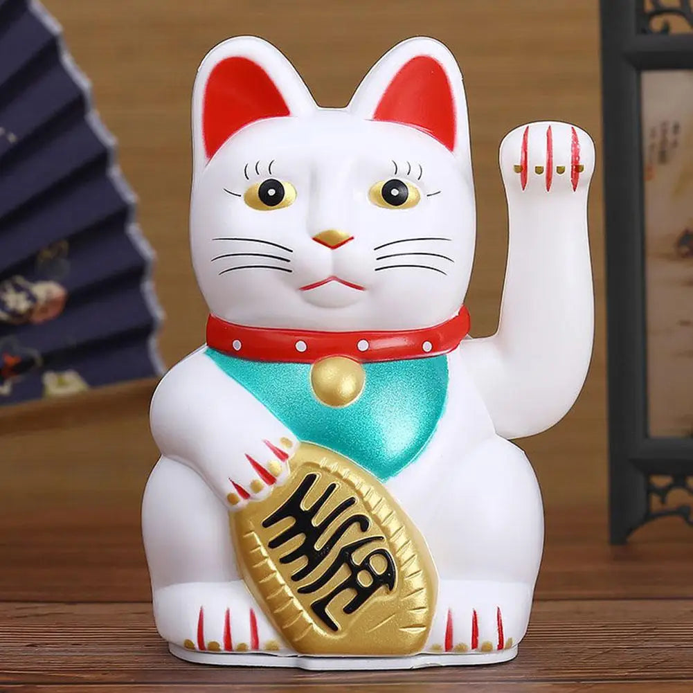 A white ceramic figurine of a cat with red ears and markings, wearing a red collar and holding a gold coin.