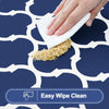 A hand wipes a textured cleaning pad on a dark blue patterned tablecloth.