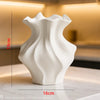 White ceramic vase with a textured wave pattern displayed on a marble surface.