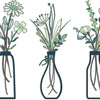Set of three rustic metal flower arrangements in glass vases with green foliage.
