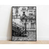 A vertical canvas art print depicting a street scene with an old bicycle parked in front of a building facade.