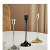 A set of three elegant metal candlesticks in silver, black, and gold displayed on a white surface.