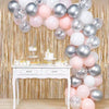 A backdrop featuring a cascade of silver and pink metallic foil tinsel fringe balloons against a gold sequin curtain.