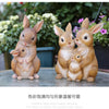 A set of hand-painted resin rabbit garden statues in various sizes sitting on a stone surface.