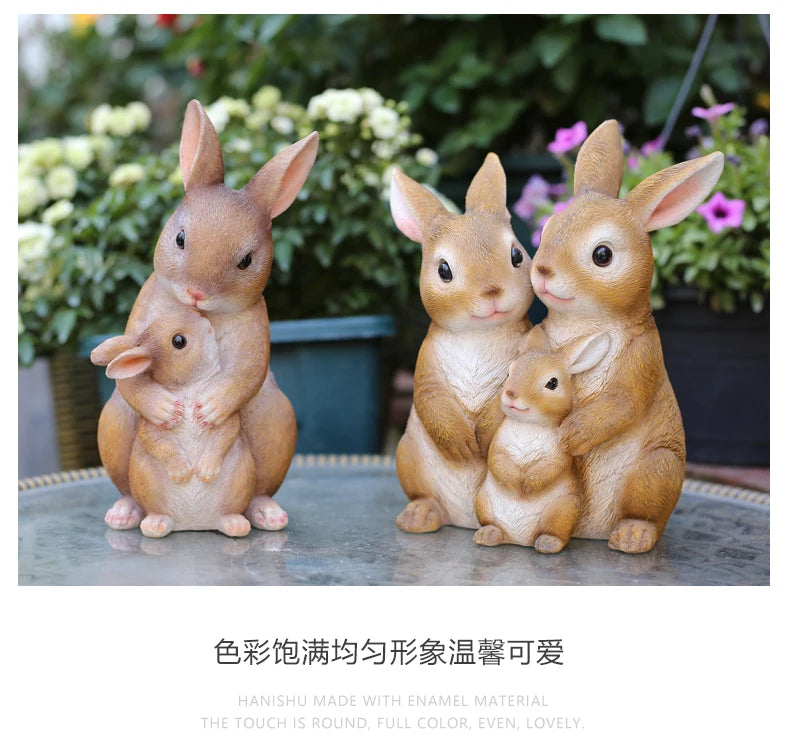 A set of hand-painted resin rabbit garden statues in various sizes sitting on a stone surface.