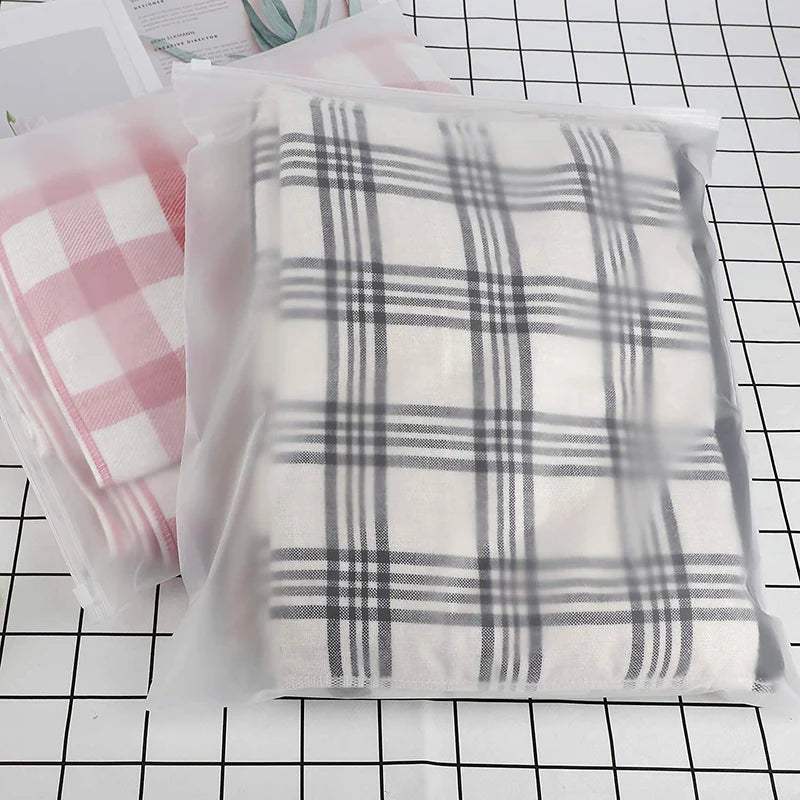 A plaid fabric storage bag filled with folded clothing, displayed on a grid background.