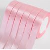 A stack of pink silk satin ribbons rolled and stacked for crafting.