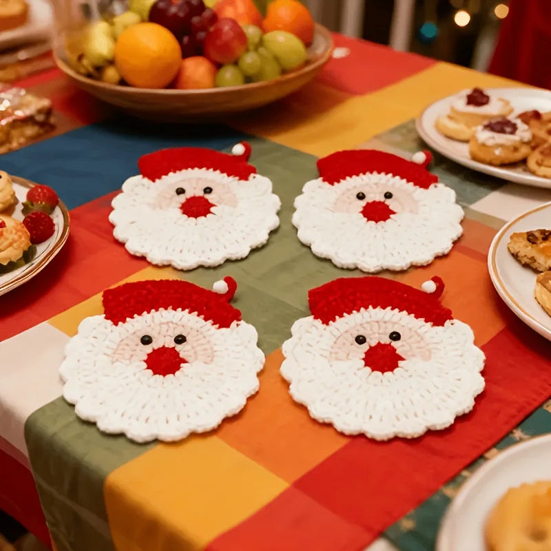 A set of handmade crochet Santa Claus coasters displayed on a colorful tablecloth.