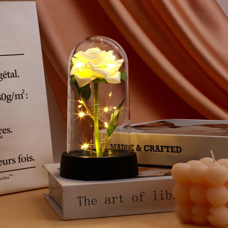 A glass dome containing a glowing yellow rose, displayed on a wooden box.