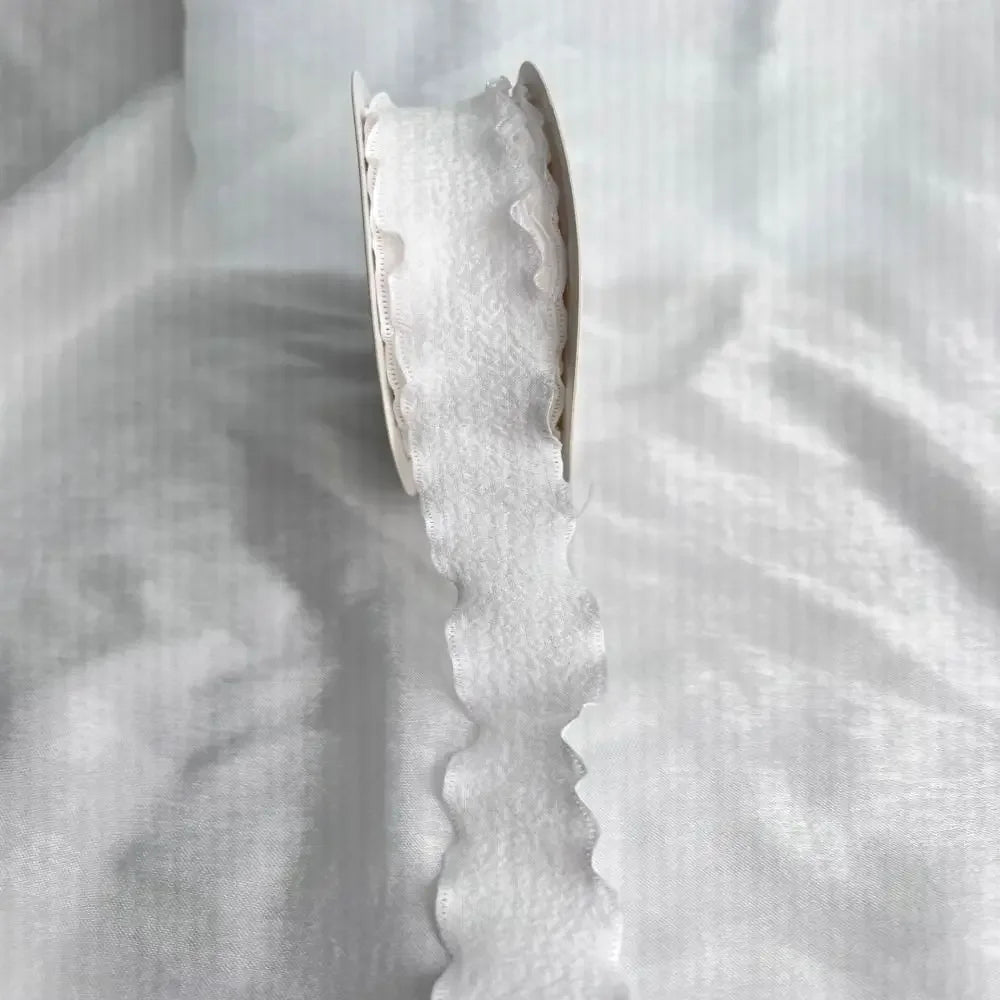 A close-up of a white decorative fishtail yarn ribbon, showing its texture and shape.