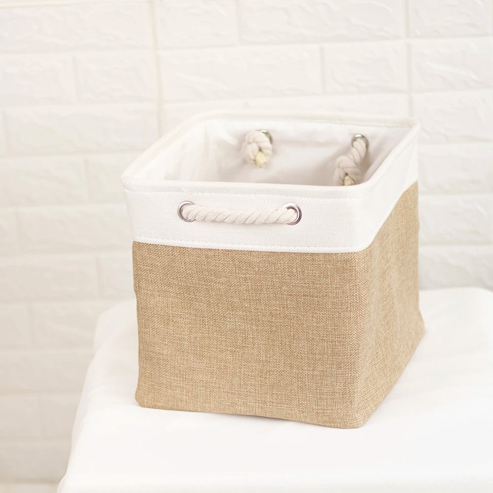 A beige fabric storage cube with a white metal frame and a woven handle, holding small white items.