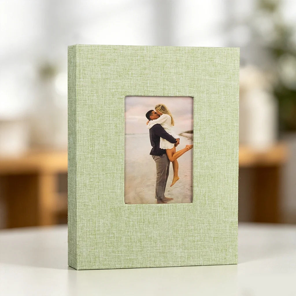 A light green linen photo album with a square display window featuring a photo of a couple embracing.