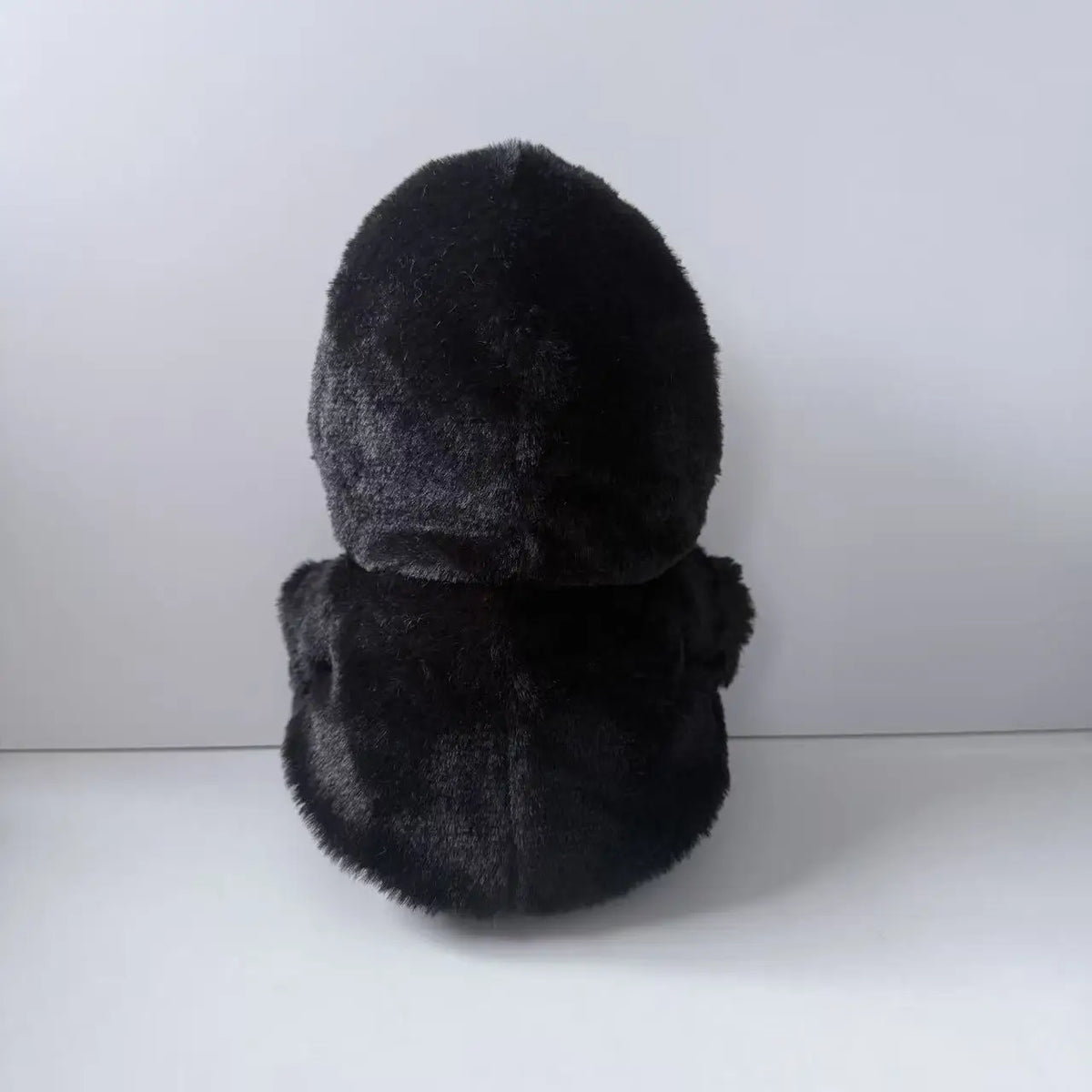 A black plush toy resembling a ghost face, soft and scary, shown from the top.