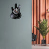 A black vintage vinyl record guitar wall clock mounted on a gray wall.