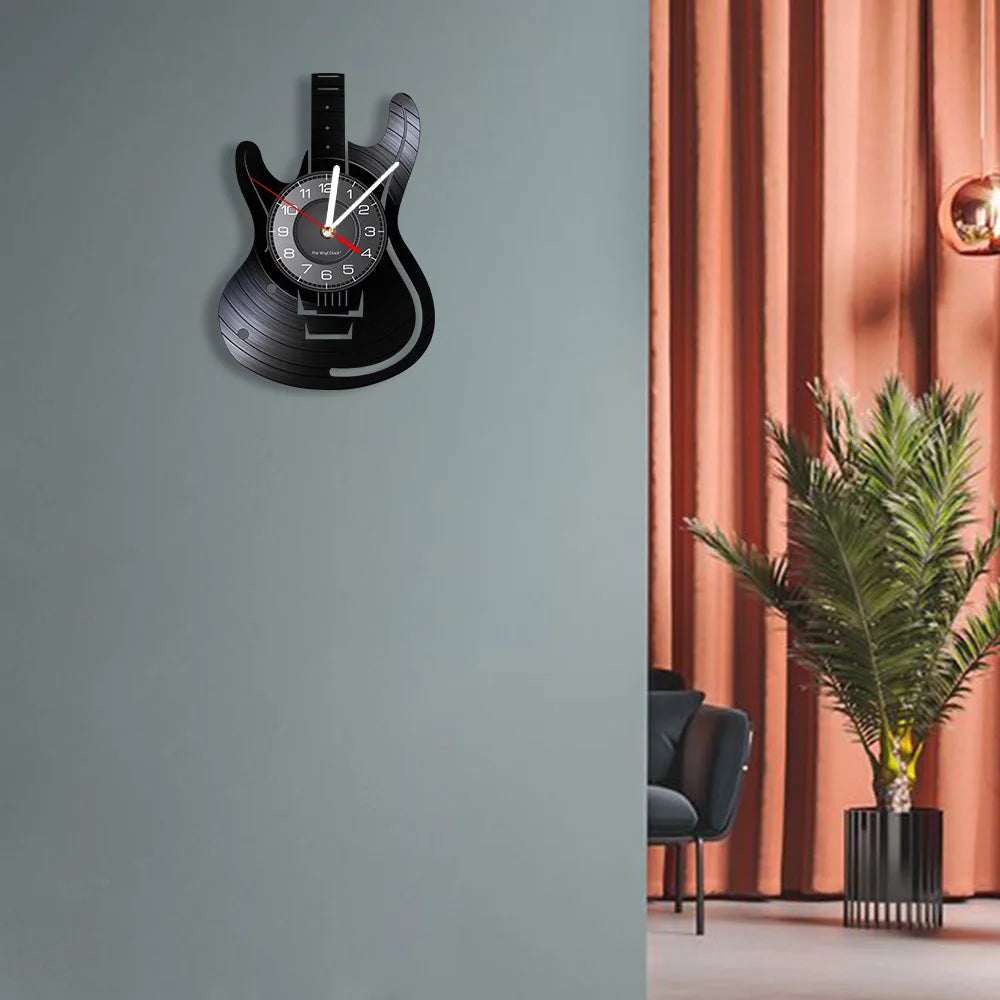 A black vintage vinyl record guitar wall clock mounted on a gray wall.