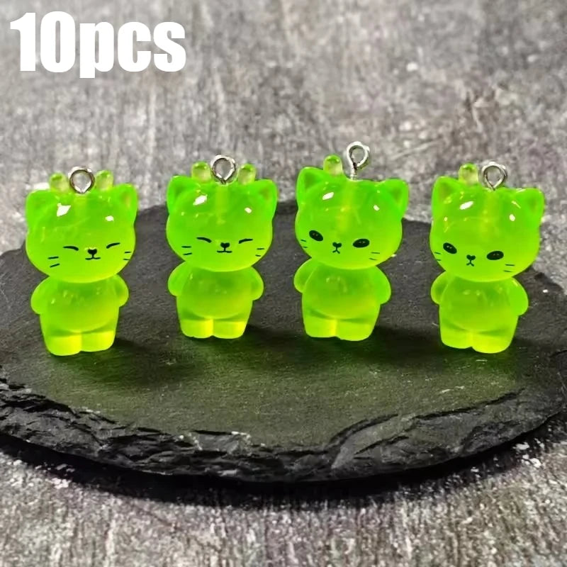 Ten glow-in-the-dark green cartoon kitty duck resin charms displayed on a dark surface.