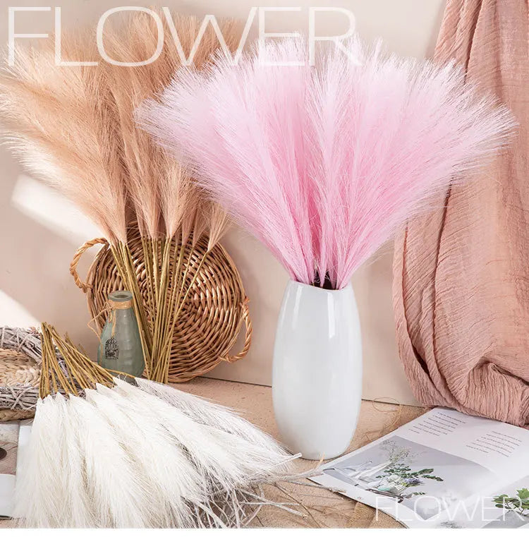 A bouquet of fluffy pink pampas grass stems in a white vase, set against a neutral background.