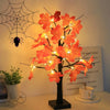 Un arbre de bouleaux noirs artificiel décoré de lumières LED orange vif sur fond blanc.