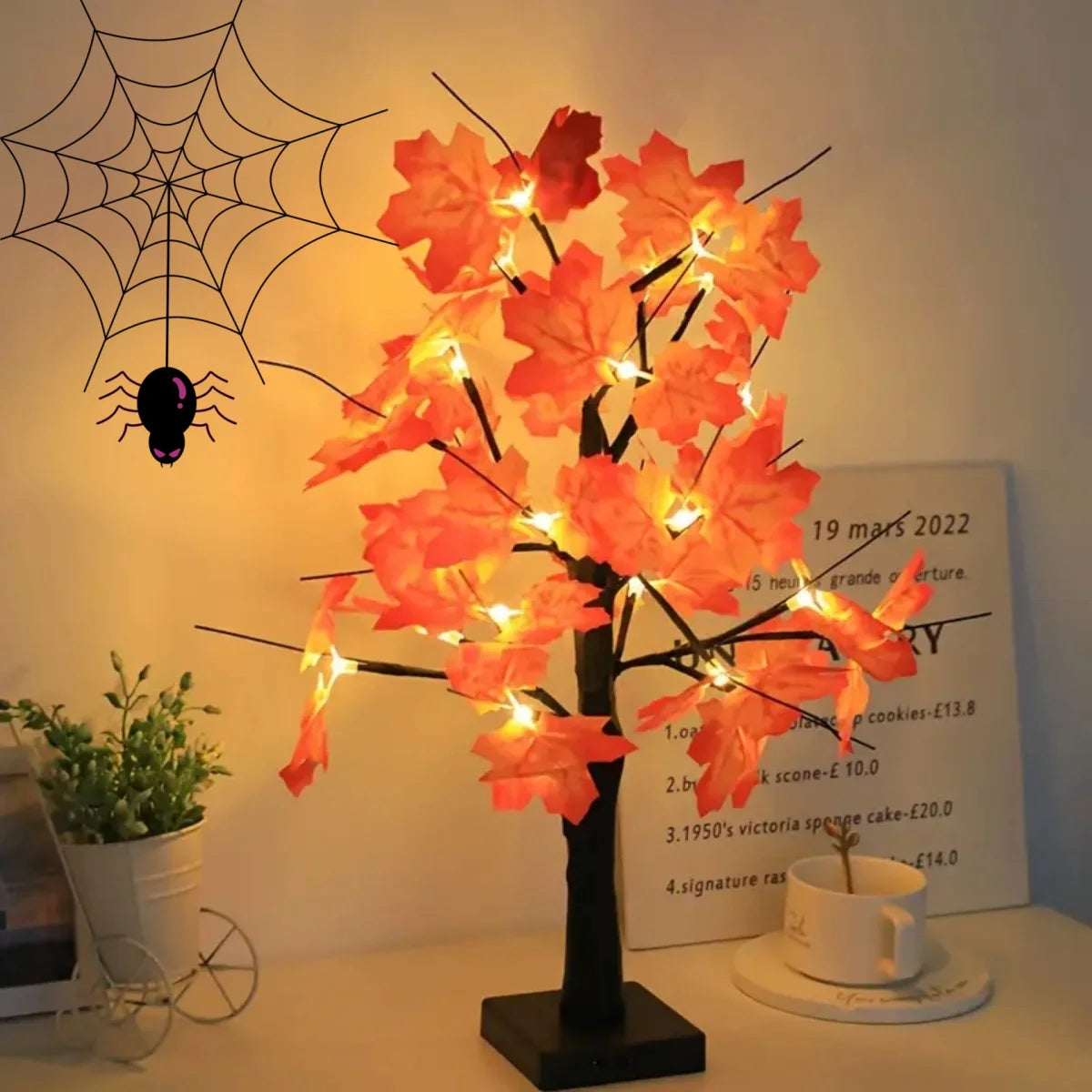 Un arbre de bouleaux noirs artificiel décoré de lumières LED orange vif sur fond blanc.