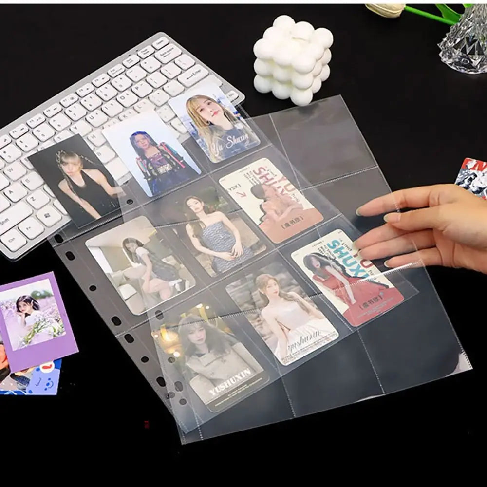 Hoja de carpeta transparente con varias photocards de Kpop y un accesorio de pompon blanco.