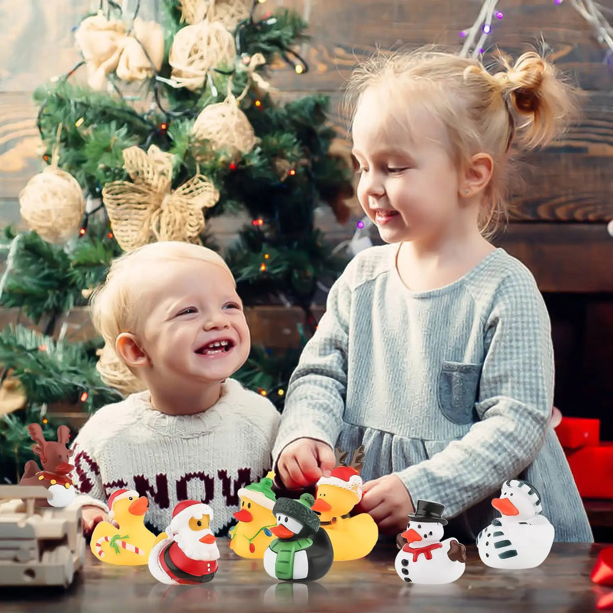 A young girl is interacting with a set of Christmas rubber ducks and toys on a wooden surface.
