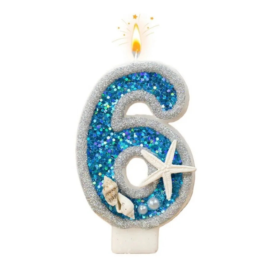 A silver glitter number six candle decorated with blue iridescent glitter and a starfish design