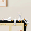 A white resin cartoon duck figurine with yellow feet is displayed on a black surface.