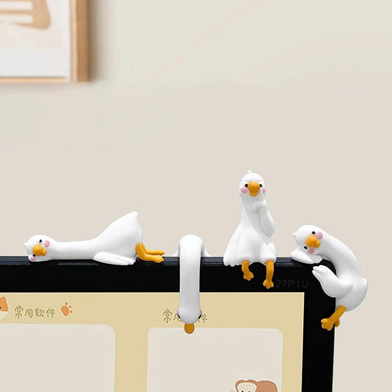 A white resin cartoon duck figurine with yellow feet is displayed on a black surface.