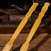 Two light yellow bamboo extended handle back scratchers shown on a wooden surface.