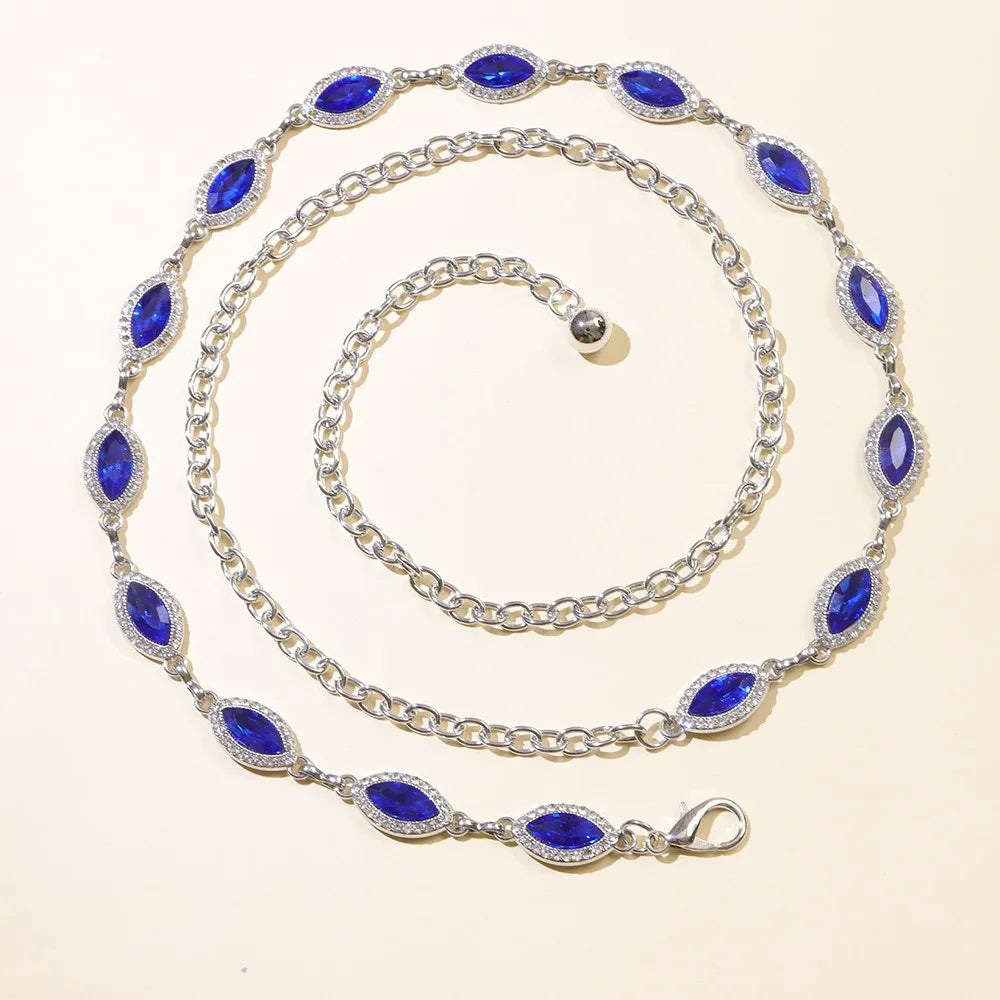 A silver chain bracelet featuring blue crystal accents, displayed on a light background.