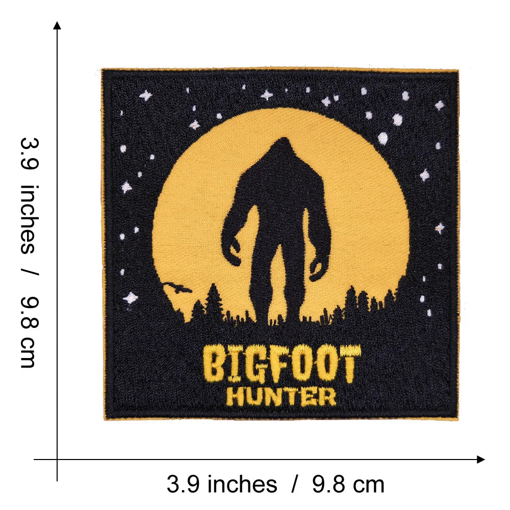 Black embroidered patch featuring a silhouette of Bigfoot against a yellow moon and starry night background.