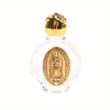 A clear glass bottle with a gold-colored stopper and an oval religious sculpture inside.