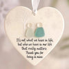 A white heart-shaped ornament featuring a frosted tree design and two small, pale green keepsake pendants.