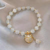 A bracelet made of small, round, milky white natural stones strung together on a gold-toned chain.