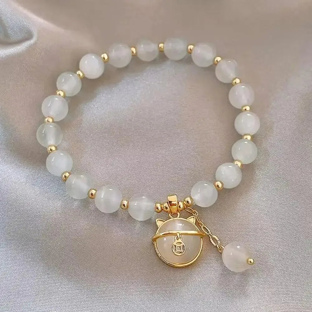 A bracelet made of small, round, milky white natural stones strung together on a gold-toned chain.