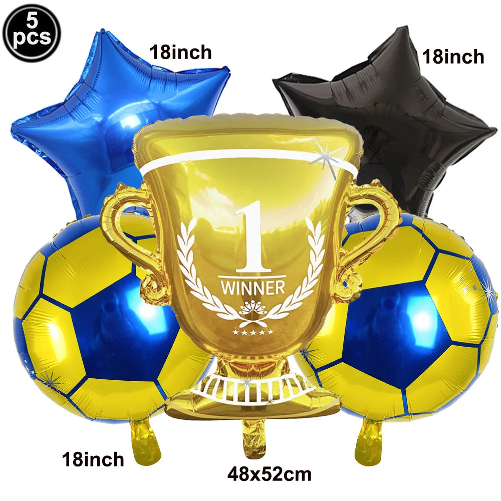 A gold trophy balloon is displayed with several blue and gold soccer balls and a black balloon, suitable for a football party