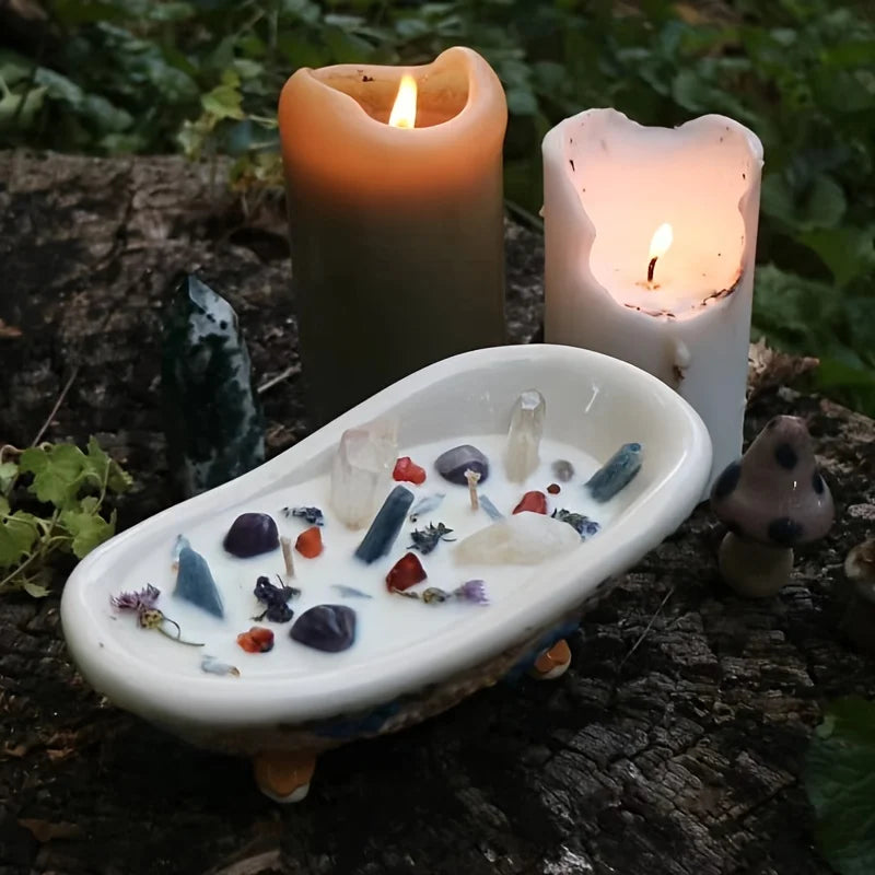 A white silicone mold for a bathtub candle jar and wax storage box sits next to two lit candles on a wooden surface.