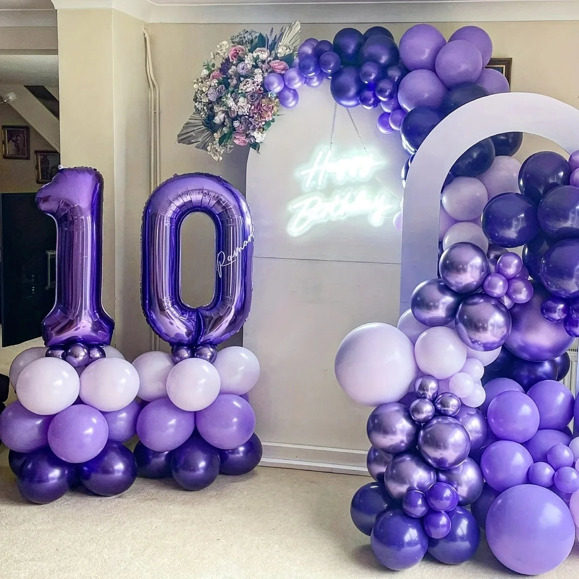 Purple foil number balloons spelling '10' and a balloon arch decoration for a birthday celebration