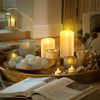 A collection of glowing LED candles and natural elements arranged on a wooden surface with an open book.