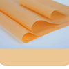 A stack of orange non-stick baking sheets rolled up on a white surface.