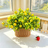 A potted arrangement of bright yellow-green lemon branches with leaves on a white table near a window.