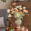 Elegant ceramic vase filled with white and peach flowers displayed on a wooden table.
