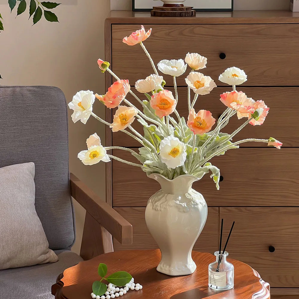 Elegant ceramic vase filled with white and peach flowers displayed on a wooden table.