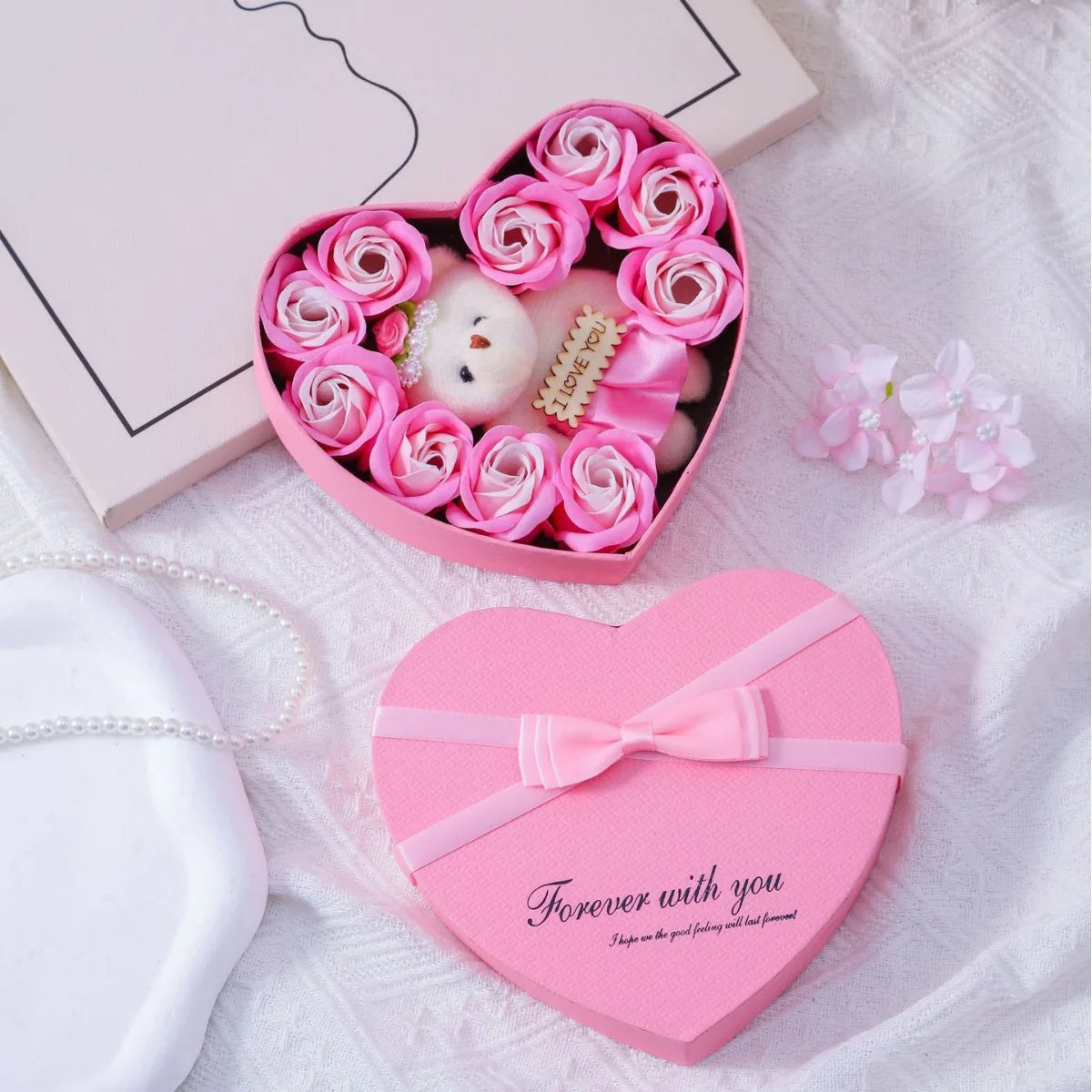 Pink heart-shaped gift box filled with artificial roses and a white plush bear