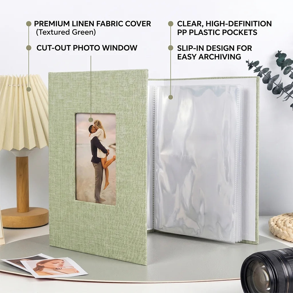 A linen photo album with a textured green cover and a clear window displaying a photograph, shown next to plastic pockets.