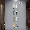 Silver acrylic wall stickers spelling out HOME with a butterfly motif on a gray wall.