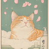A fluffy orange tabby cat is relaxing in a bath of foam surrounded by pink cherry blossoms.
