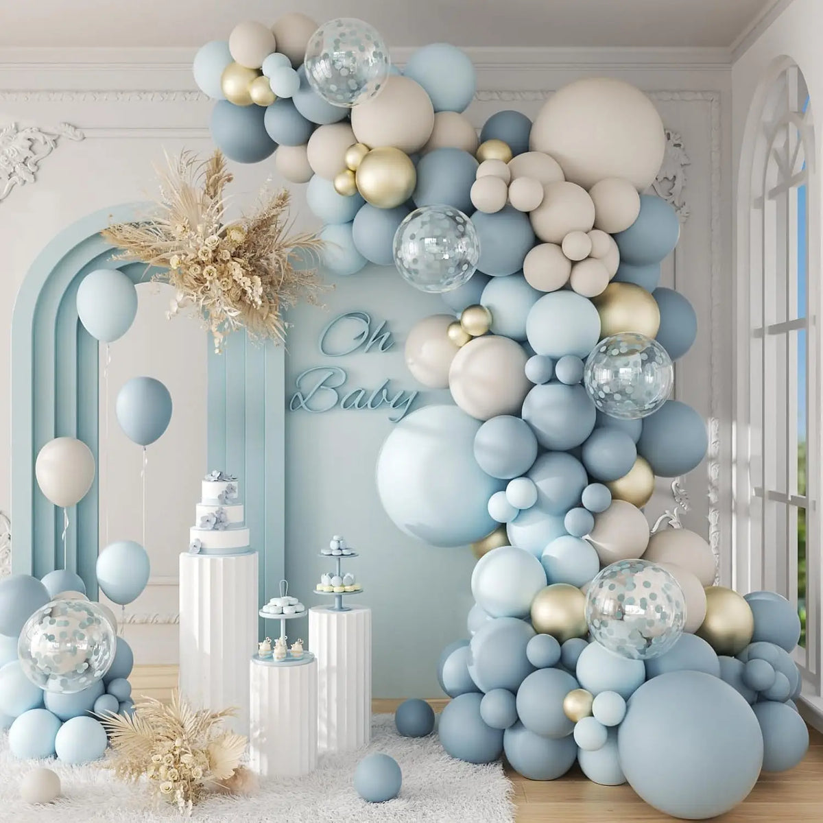 Decoración para baby shower con un gran arco de globos en tonos azules suaves y beige con detalles dorados.